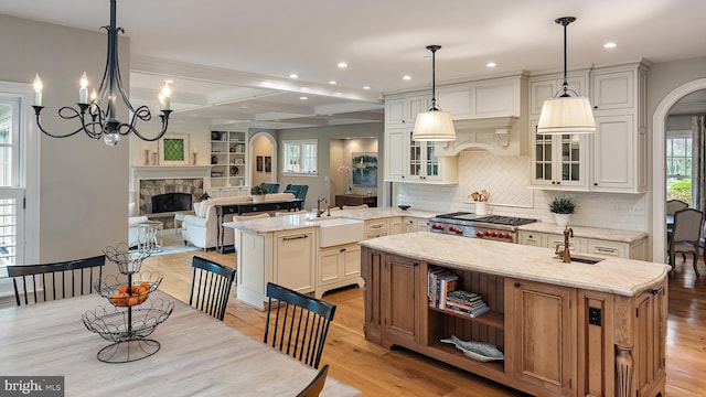 208 Wardour Dr, Annapolis, MD 21401 - kitchen featuring a stone fireplace, light wood-style floors, a kitchen island with sink, stove, and recessed lighting