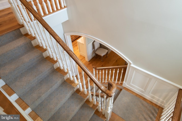 208 Wardour Dr, Annapolis, MD 21401 - staircase with a wainscoted wall, a towering ceiling, wood finished floors, arched walkways, and a decorative wall