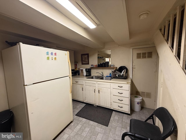 kitchen featuring a sink, visible vents, light countertops, and freestanding refrigerator