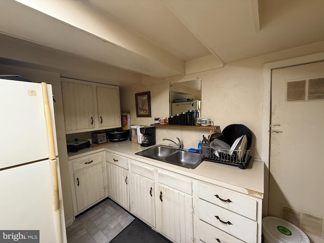 kitchen with light countertops, visible vents, a sink, and freestanding refrigerator