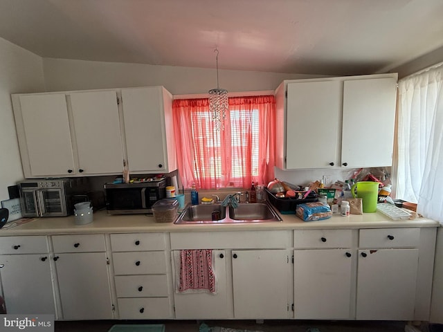 kitchen featuring stainless steel microwave, white cabinets, a sink, and vaulted ceiling