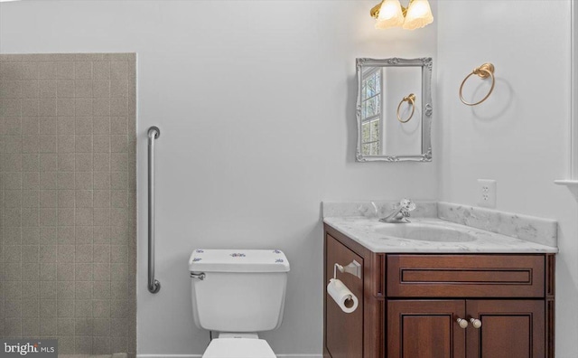 bathroom featuring a tile shower, toilet, and vanity