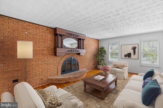 living room featuring brick wall, a textured ceiling, wood finished floors, and a fireplace