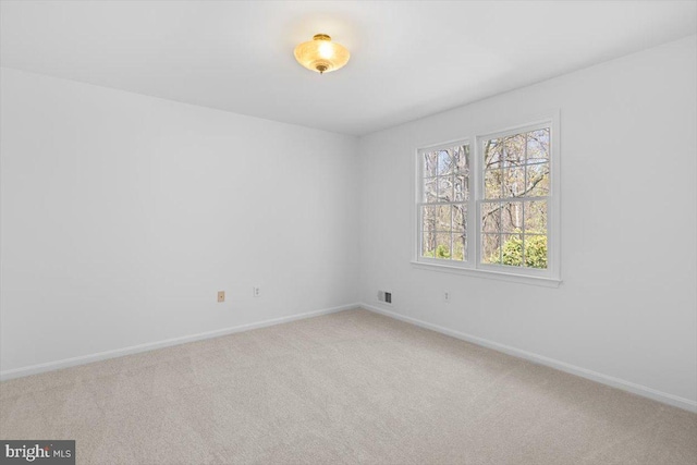 empty room featuring visible vents, baseboards, and carpet