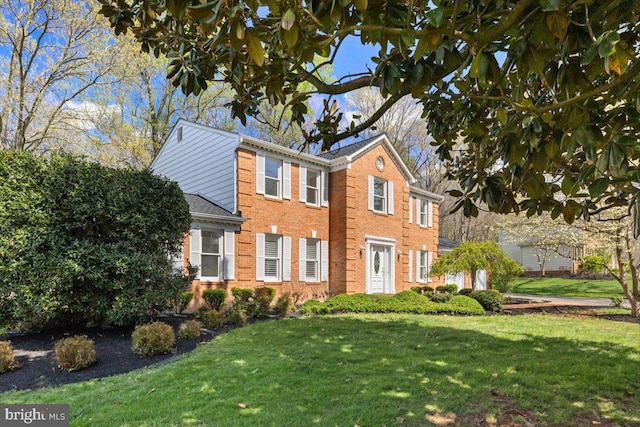 colonial house with a front lawn and brick siding