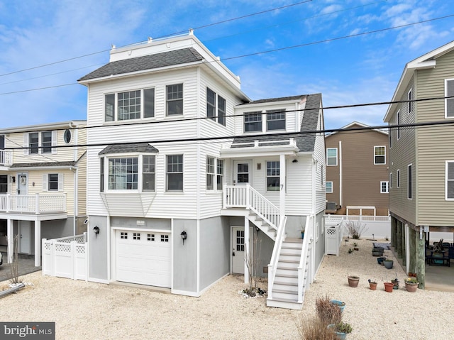 view of front facade with a garage, roof with shingles, fence, stairs, and driveway