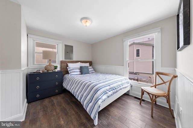 bedroom with dark wood-style floors, wainscoting, and electric panel