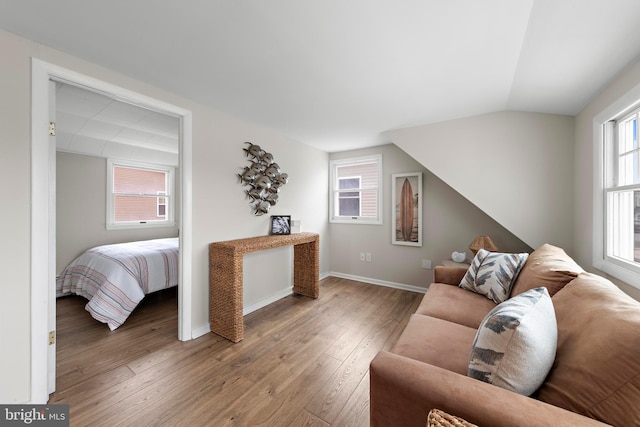 living area featuring baseboards, wood-type flooring, and lofted ceiling