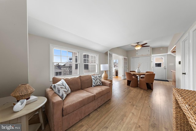 living area featuring a ceiling fan, light wood-style floors, and lofted ceiling
