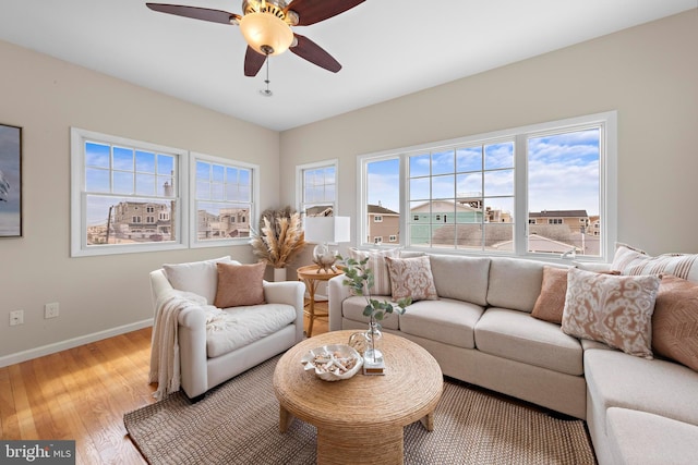 living room with light wood-type flooring, baseboards, and a ceiling fan