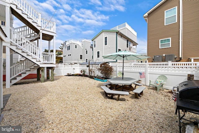 view of yard featuring central AC unit, a residential view, fence private yard, and stairs