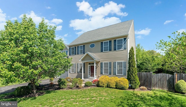 colonial inspired home featuring fence and a front lawn