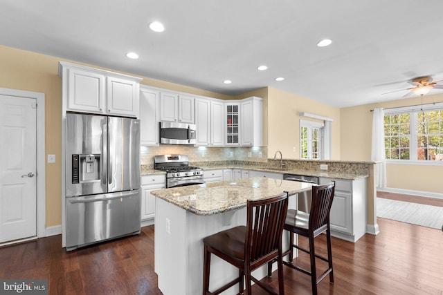 kitchen with a sink, baseboards, stainless steel appliances, and a peninsula