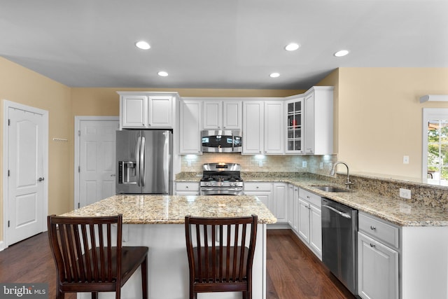 kitchen featuring a sink, appliances with stainless steel finishes, a kitchen breakfast bar, and dark wood-style flooring