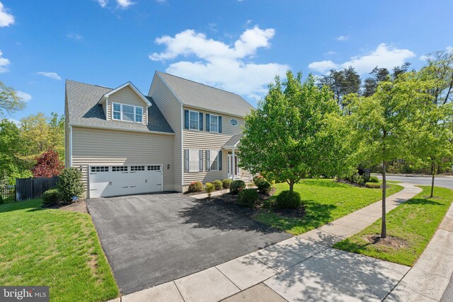colonial home featuring fence, driveway, a front lawn, and a garage