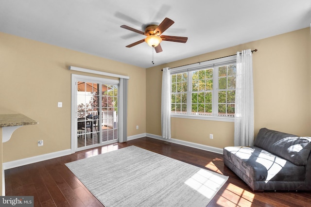 living area featuring baseboards, a ceiling fan, and a healthy amount of sunlight