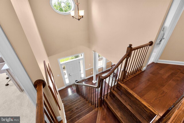 entrance foyer featuring wood-type flooring, baseboards, a towering ceiling, and a chandelier