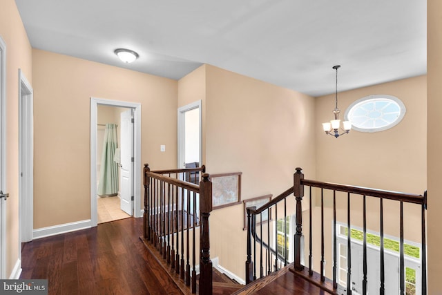corridor featuring baseboards, an upstairs landing, a healthy amount of sunlight, and wood finished floors