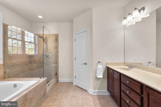 bathroom with a shower stall, a relaxing tiled tub, vanity, tile patterned floors, and baseboards