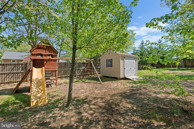 view of yard featuring a playground, a storage unit, an outdoor structure, and a fenced backyard