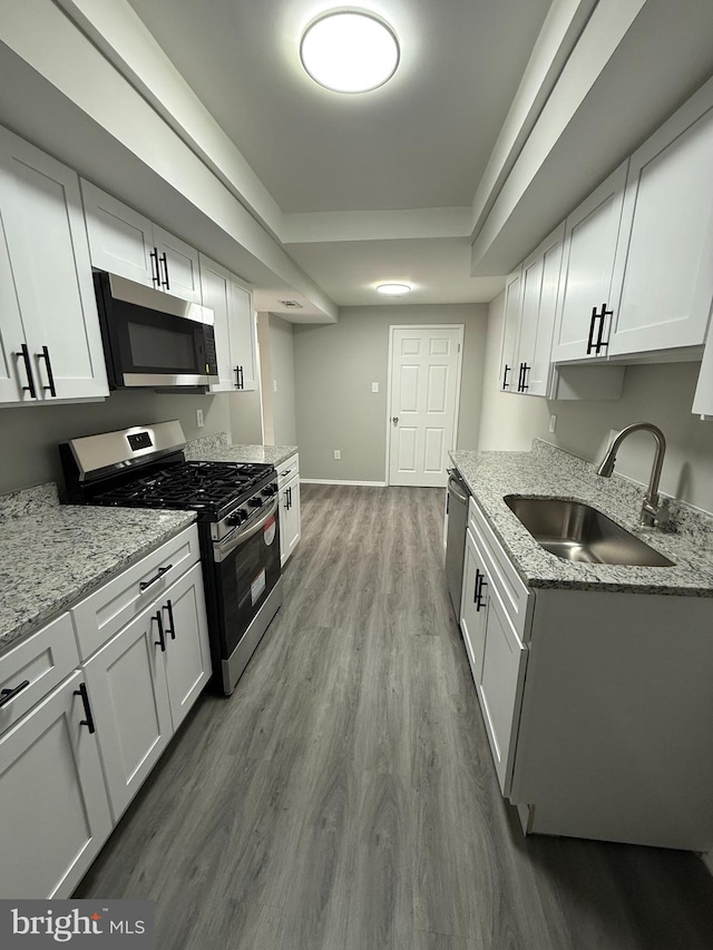 10224 Prince Pl Unit 12-307, Upper Marlboro, MD 20774 - kitchen featuring white cabinets, stainless steel appliances, a raised ceiling, wood finished floors, and a sink