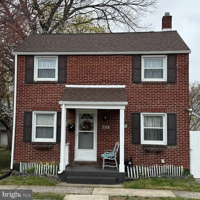 townhome / multi-family property with a chimney, brick siding, and roof with shingles