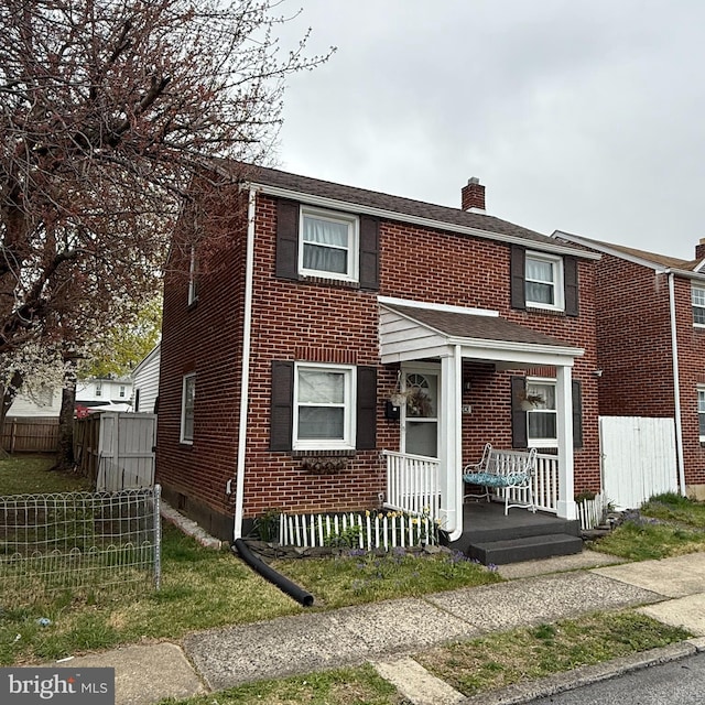 multi unit property featuring a chimney, a porch, brick siding, and fence
