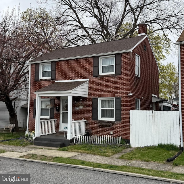 view of front of home featuring a chimney, brick siding, fence, and roof with shingles