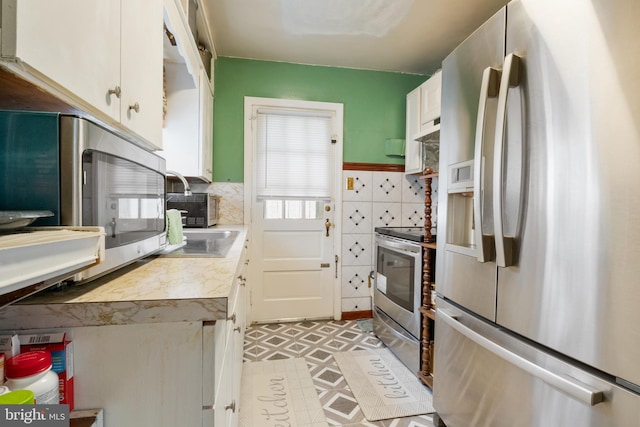 kitchen with stainless steel appliances, under cabinet range hood, white cabinetry, light countertops, and light floors