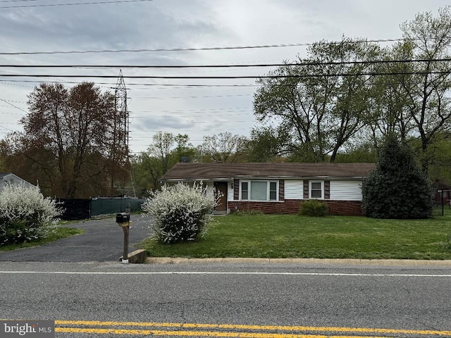 single story home featuring fence, brick siding, and a front yard