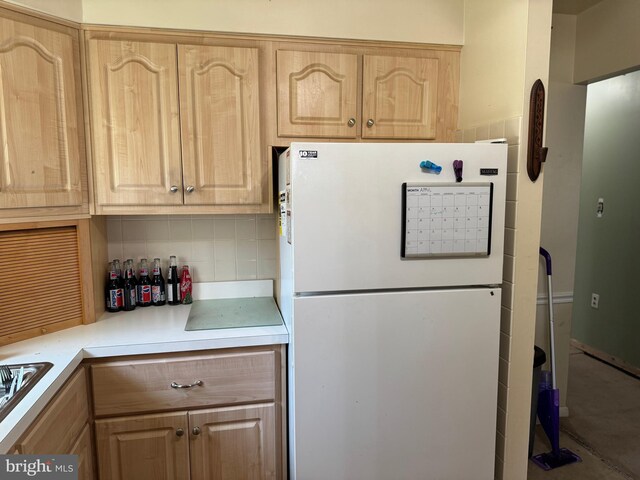 kitchen featuring light countertops, freestanding refrigerator, and light brown cabinets