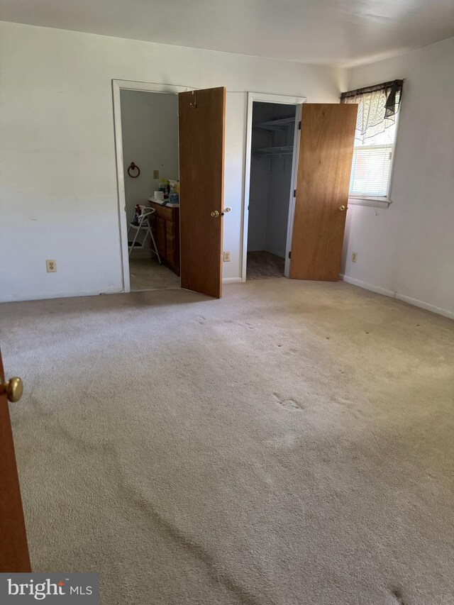 unfurnished bedroom featuring a closet and light colored carpet