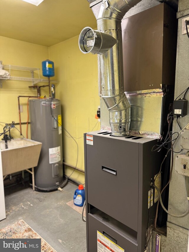 utility room featuring heating unit, electric water heater, and a sink