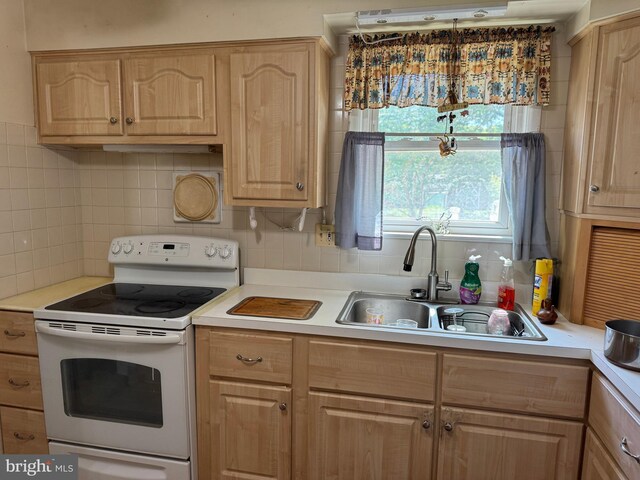kitchen featuring light brown cabinets, white range with electric stovetop, a sink, and light countertops
