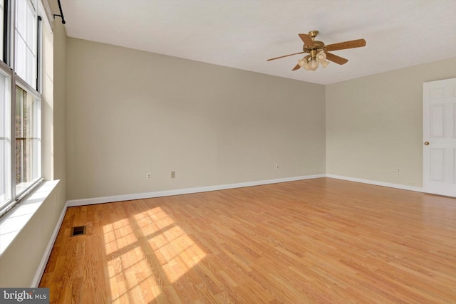empty room featuring light wood-style floors, plenty of natural light, a ceiling fan, and visible vents