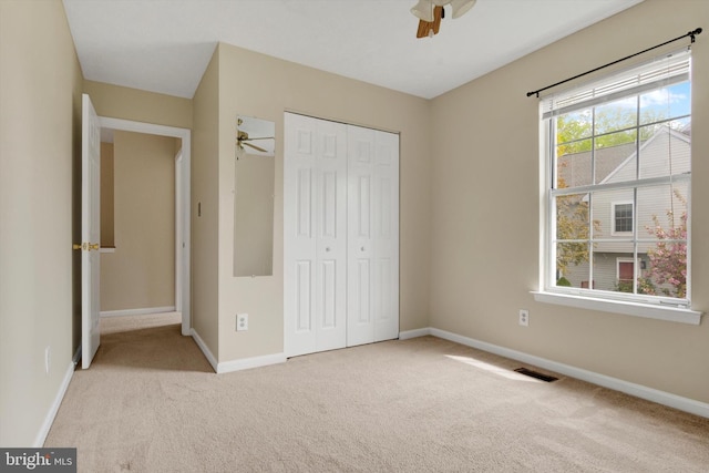 unfurnished bedroom featuring a closet, carpet flooring, baseboards, and visible vents