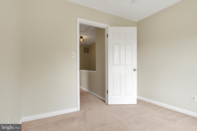 spare room featuring baseboards, light colored carpet, and visible vents