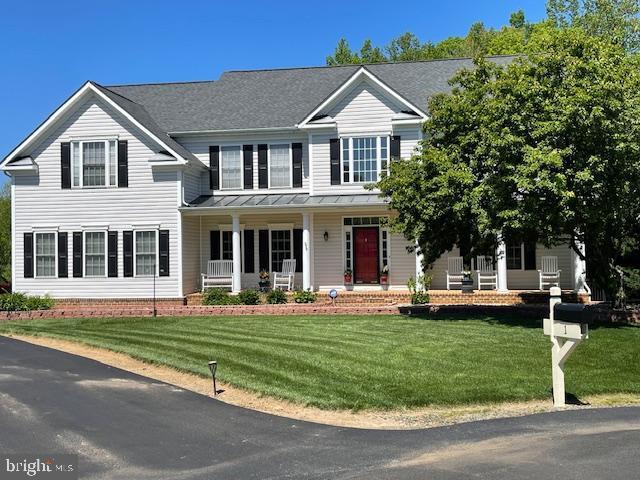 view of front of house featuring covered porch, a standing seam roof, metal roof, and a front lawn