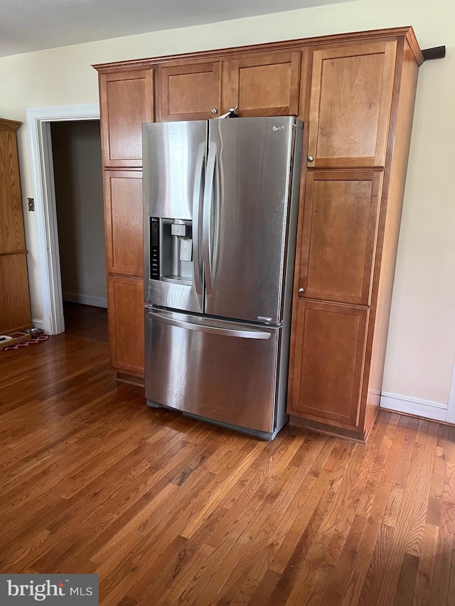 kitchen with stainless steel refrigerator with ice dispenser, dark wood-style flooring, and baseboards