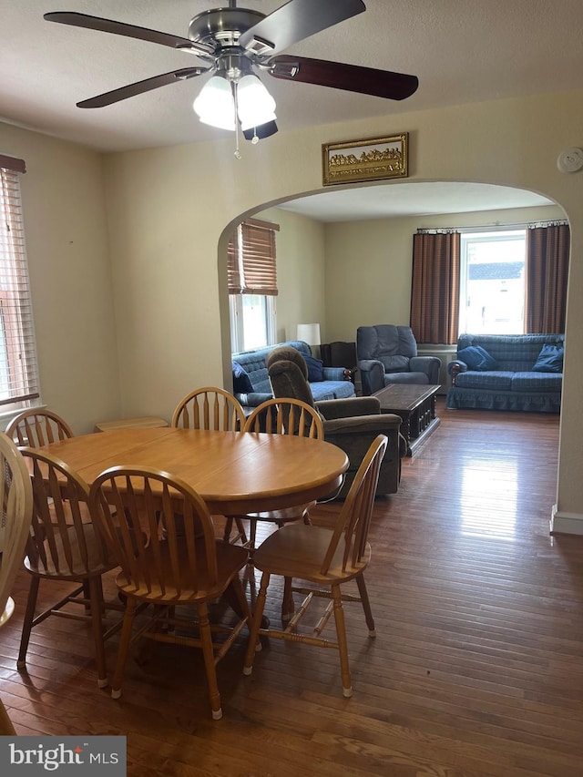 dining room with ceiling fan, arched walkways, and wood finished floors