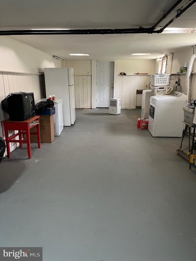 below grade area featuring separate washer and dryer, freestanding refrigerator, and a garage