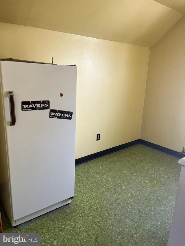 unfurnished room with vaulted ceiling and baseboards