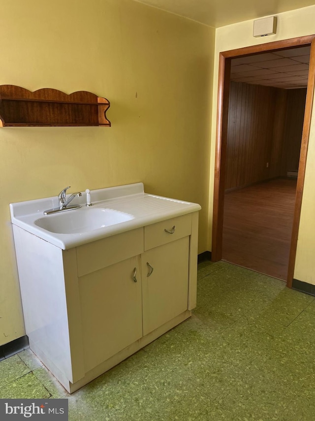 washroom with light floors, baseboards, and a sink