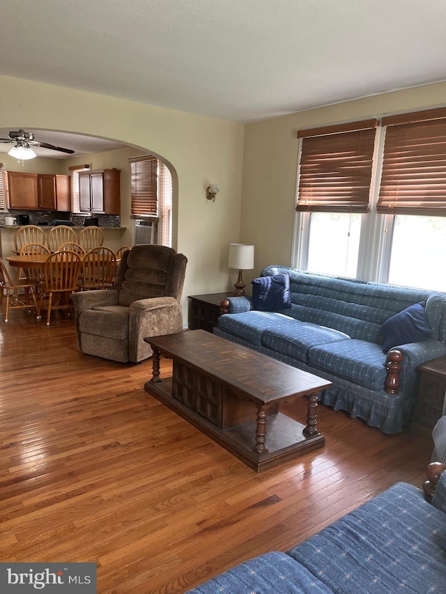 living room with cooling unit, arched walkways, ceiling fan, and wood-type flooring