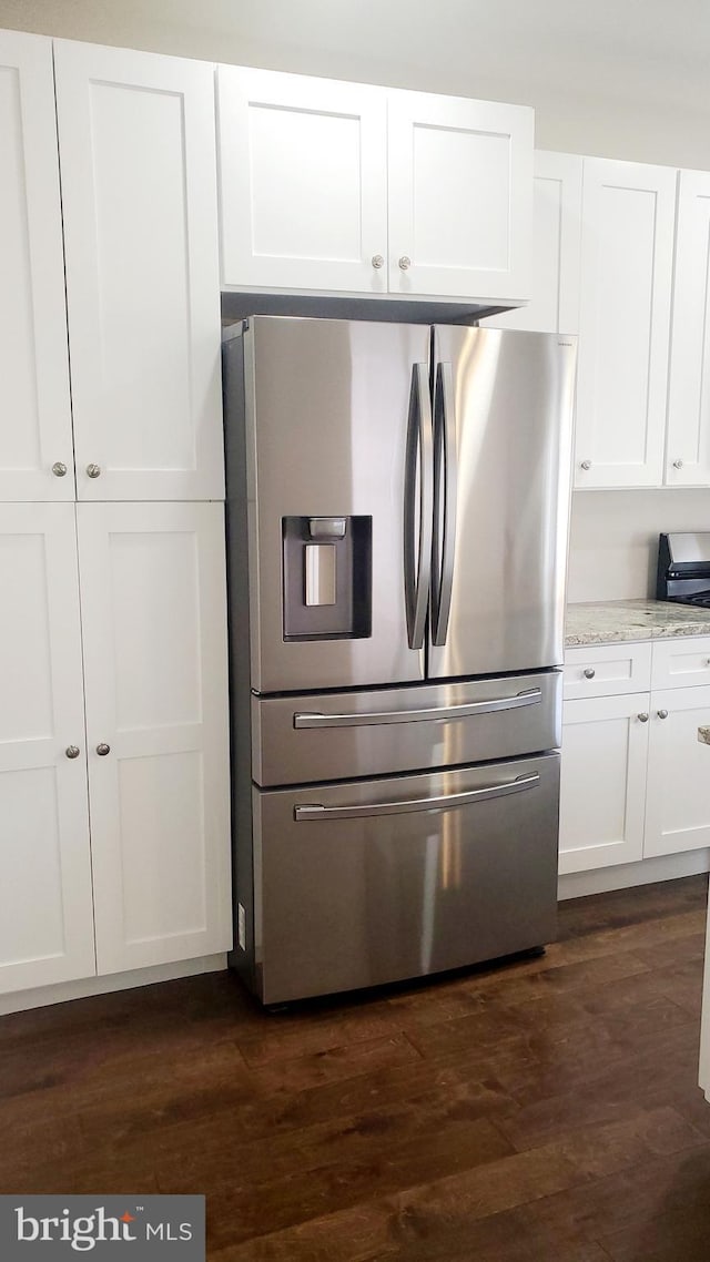 kitchen featuring dark wood-type flooring, white cabinets, stainless steel fridge, and light stone countertops