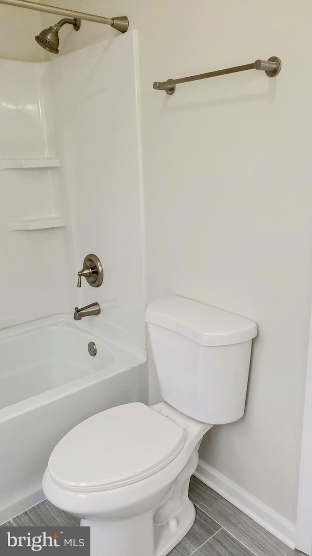 full bath with bathtub / shower combination, baseboards, and toilet