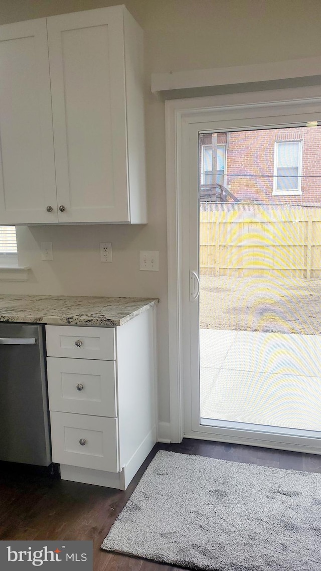 kitchen with stainless steel dishwasher, plenty of natural light, white cabinetry, and dark wood finished floors