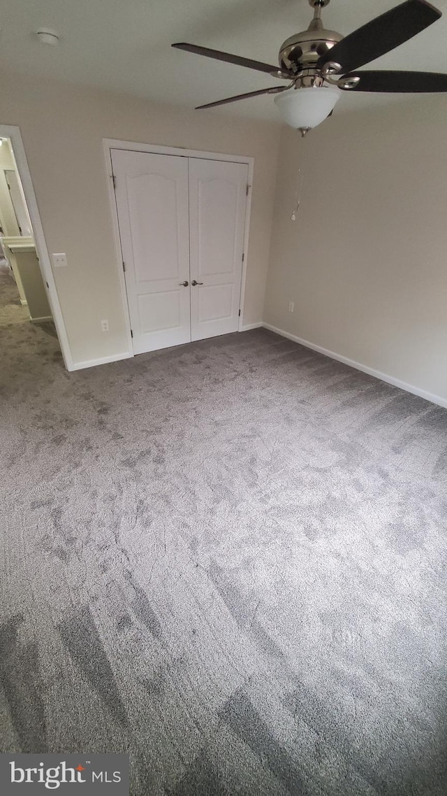 unfurnished bedroom with ceiling fan, a closet, carpet flooring, and baseboards