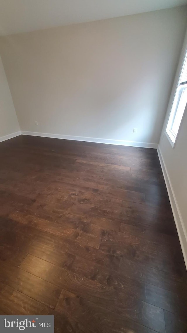 empty room featuring dark wood-type flooring and baseboards