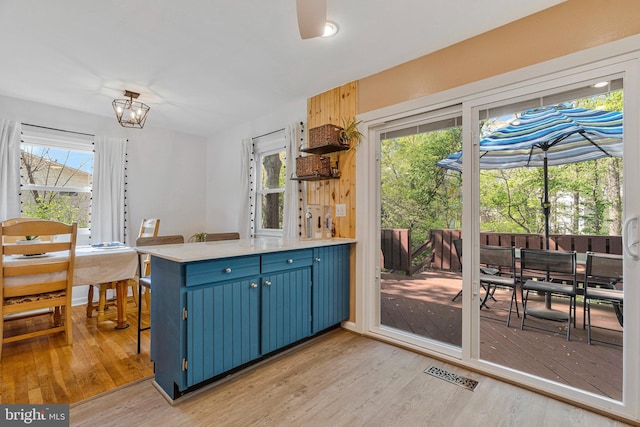 305 W Poplar Rd, Sterling, VA 20164 - kitchen featuring blue cabinets, light wood-type flooring, light countertops, a peninsula, and visible vents